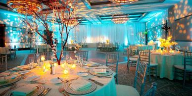 Elegant banquet hall with blue lighting and beautifully set round tables.