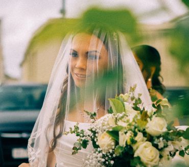 Bride smiling behind veil with flowers.