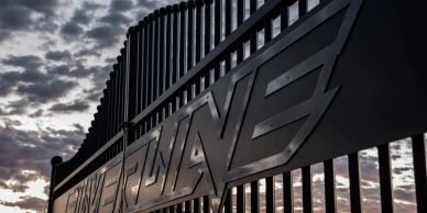 Close-up of a modern metal fence with a dramatic cloudy sky backdrop.