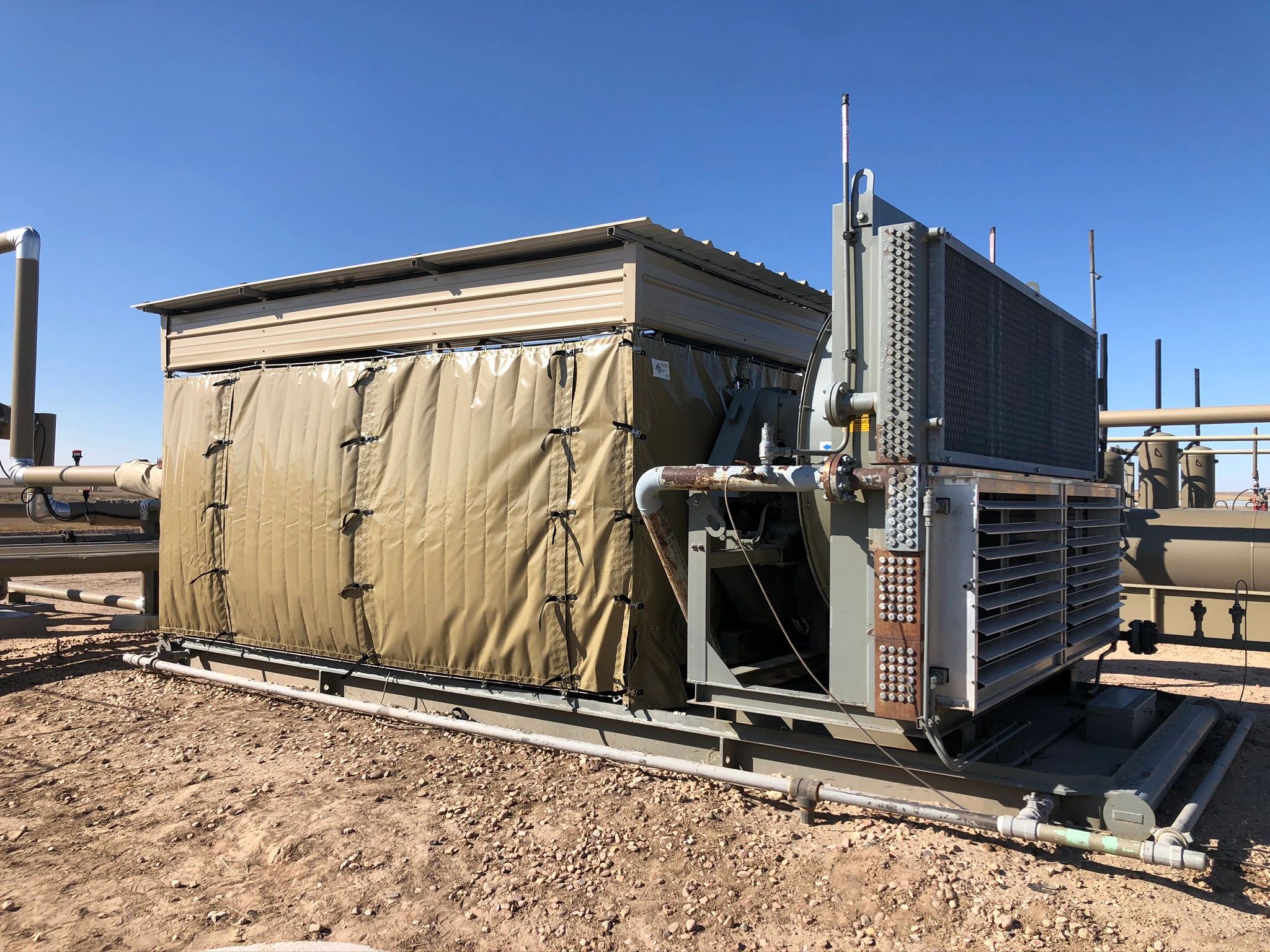 Industrial air conditioning unit outdoors on a dirt ground.
