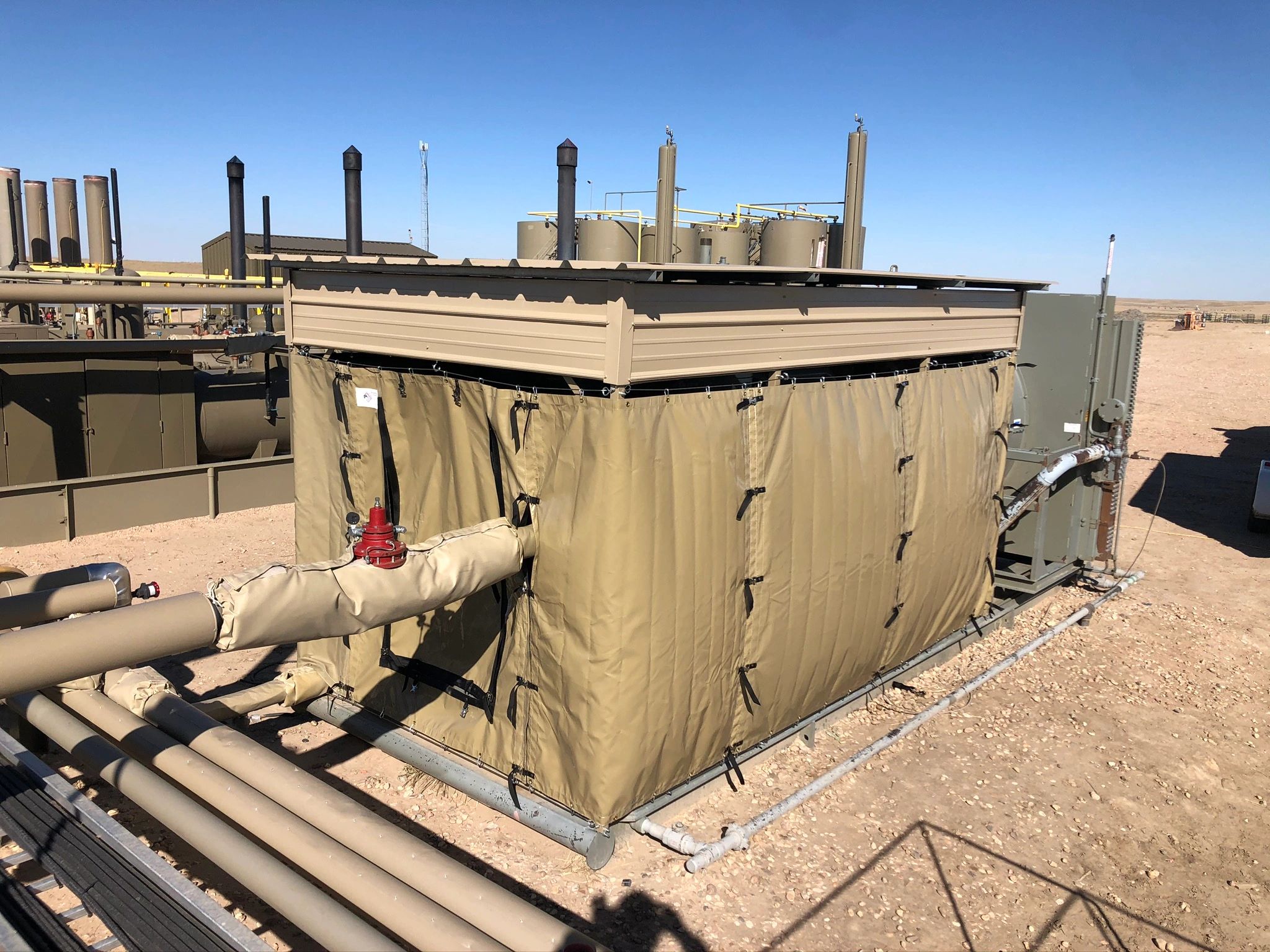 Industrial site with covered equipment and pipes.