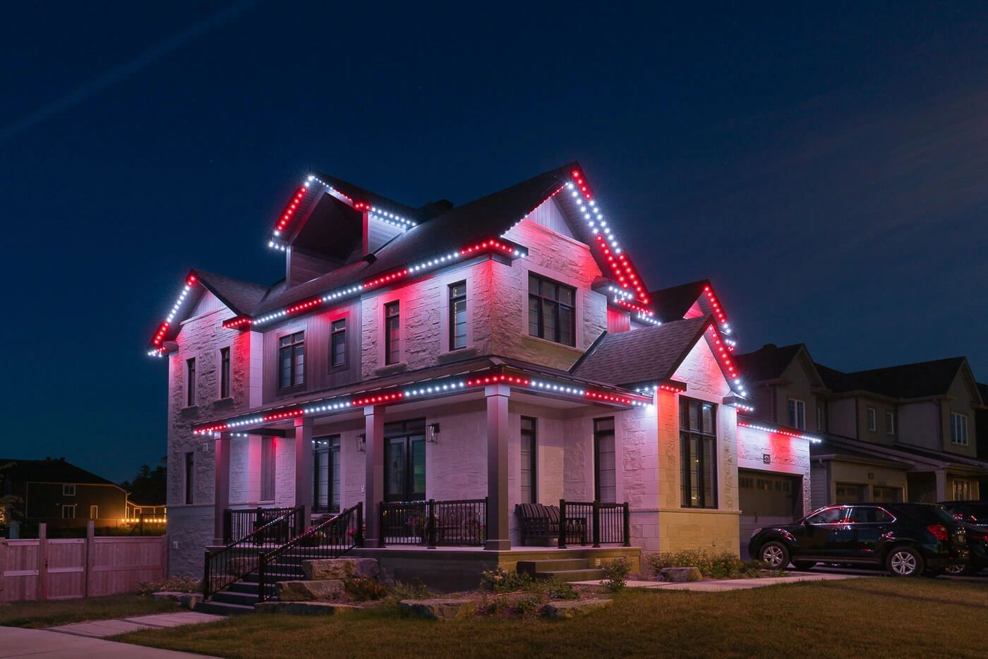 Modern house with red and white exterior lights at night.