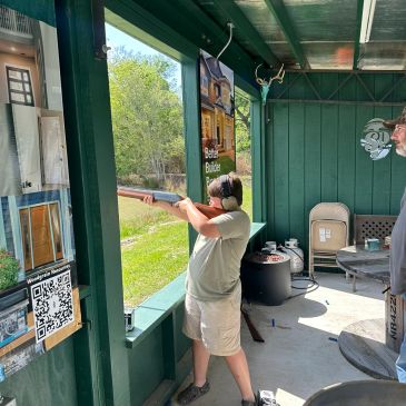 Person aiming a rifle at an outdoor shooting range.