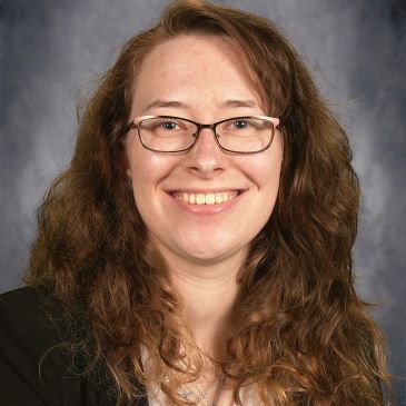 Smiling woman with glasses and curly hair.