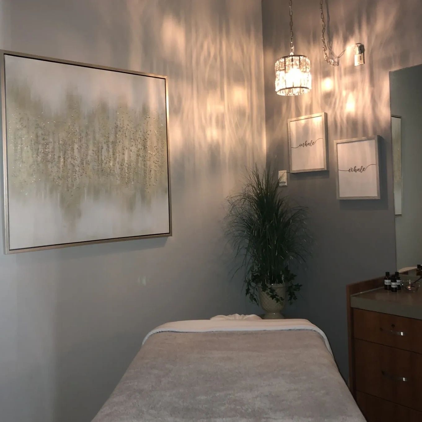Dimly lit and relaxing massage room in colors of silver, gray, white and cream.