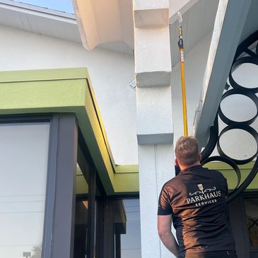 Man cleaning windows with long pole.