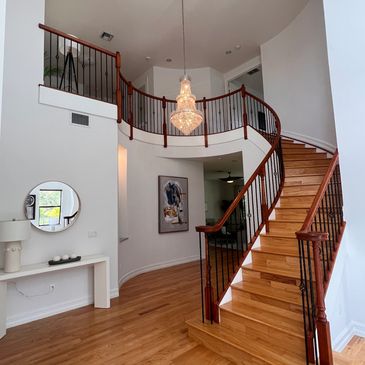 Elegant curved wooden staircase with chandelier.