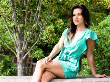 Senior pictures young woman outdoors with long dark hair wearing a teal jumper.