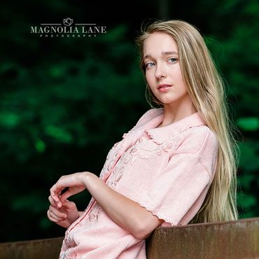 Outdoor portraits young blonde woman wearing a pink sweater in the woods.
