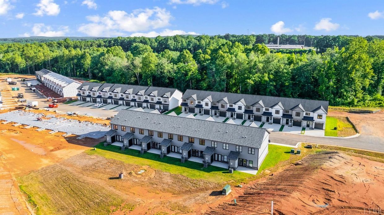 Aerial view of a new townhouse development near a forested area.
