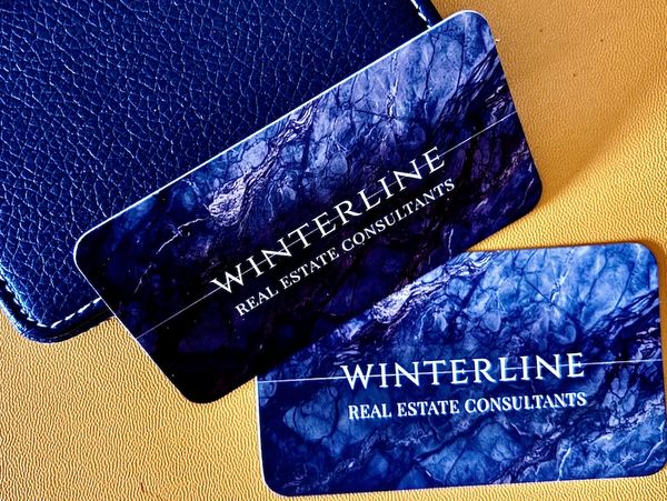 Two elegant business cards for Winterline Real Estate Consultants with a marble blue background.