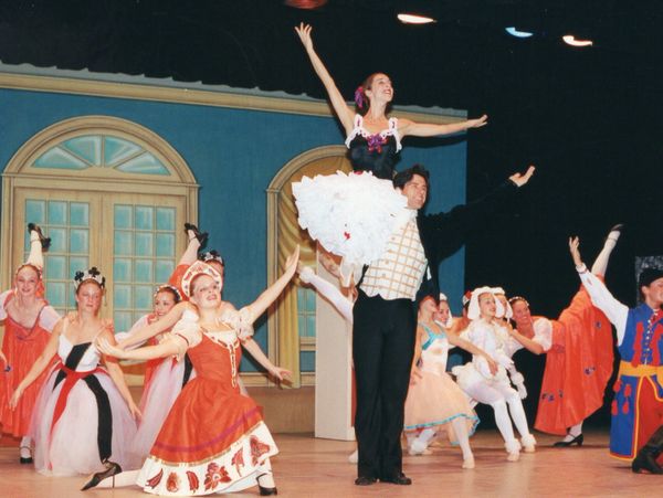 Ballet dancers performing a lively stage dance in colorful costumes.