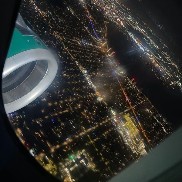 Night aerial view of a city with airplane engine visible.