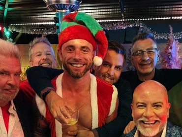 Group of men celebrating Christmas with festive attire and drinks.
