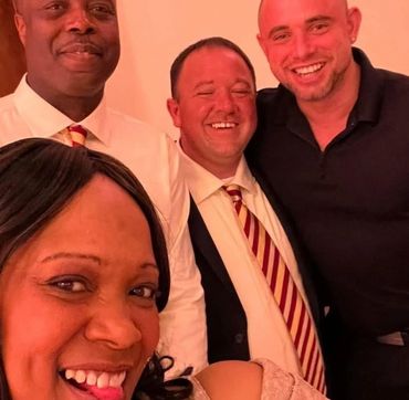 Four friends smiling and posing for a cheerful selfie indoors.