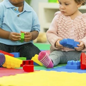 Three toddlers playing with plastic blocks