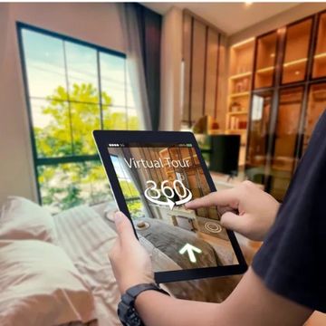 Person using a tablet for a 360-degree virtual tour inside a modern living room.