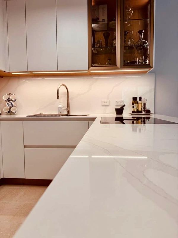 Modern kitchen with sleek white cabinetry and marble countertop.