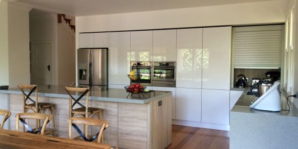 Modern kitchen with white cabinets and wooden chairs.