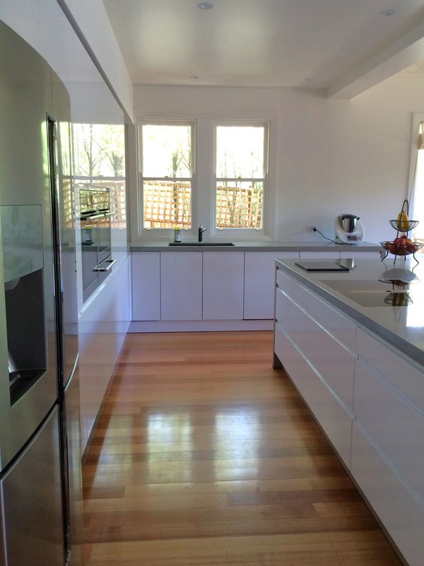 Modern kitchen with wooden flooring and white cabinets.