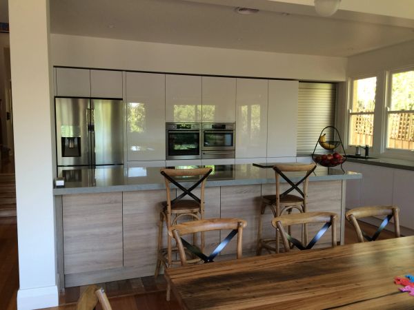 Modern kitchen with wooden chairs and stainless steel appliances.