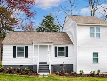 White house with black shutters and a landscaped yard.