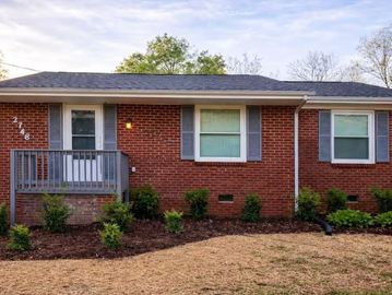 Red brick house with gray shutters and small front porch.