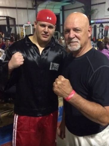 Two men posing with fists up in a gym or boxing setting.