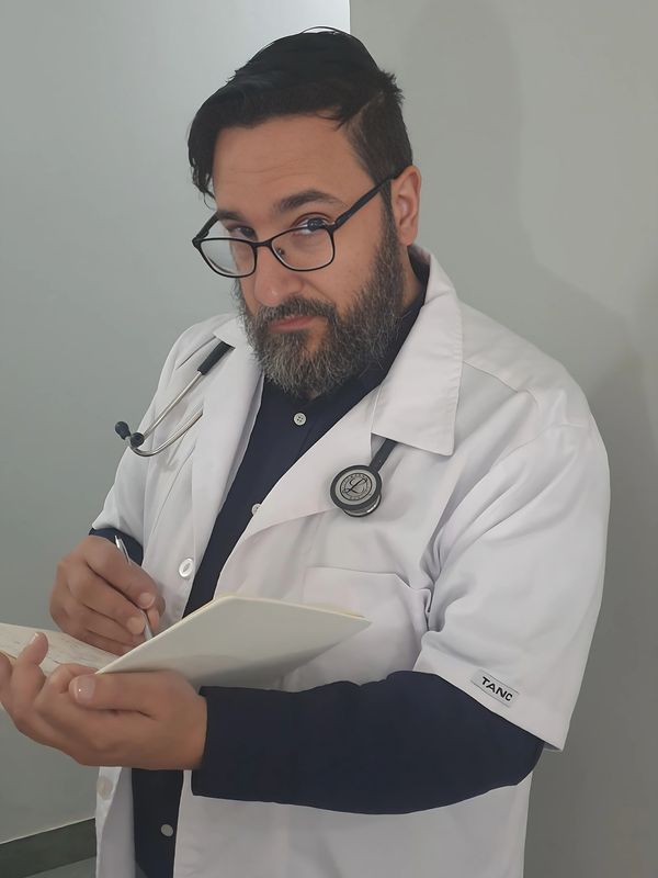Doctor in a white coat writing on a notepad with a stethoscope around his neck.