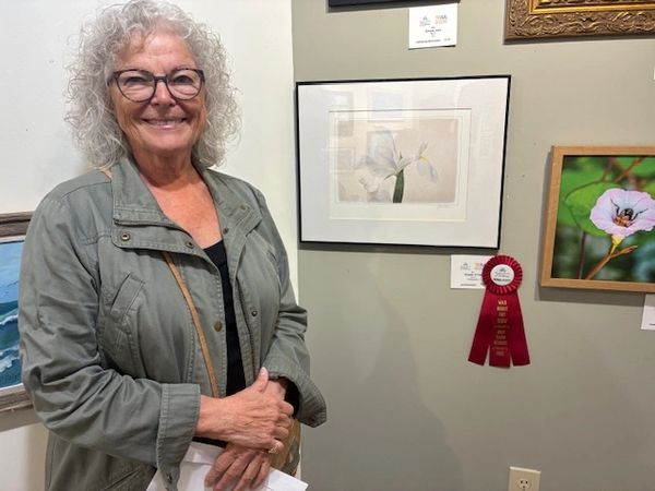 Artist in front of her photograph of a  white flower