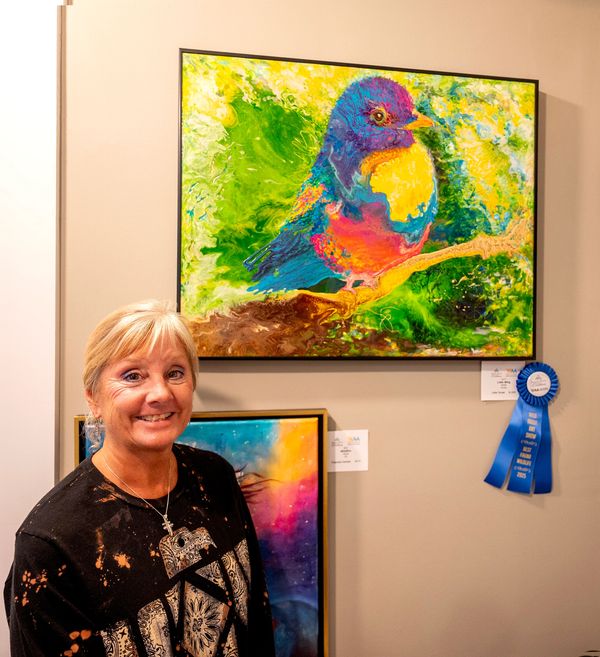 Artist in front of her painting of a Bird