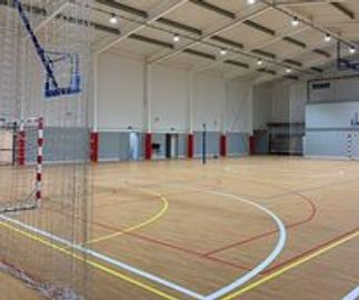 Empty indoor sports court with basketball hoops and goalposts.