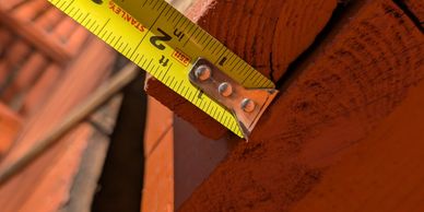 A yellow measuring tape showing about 2 inches on a wooden surface.