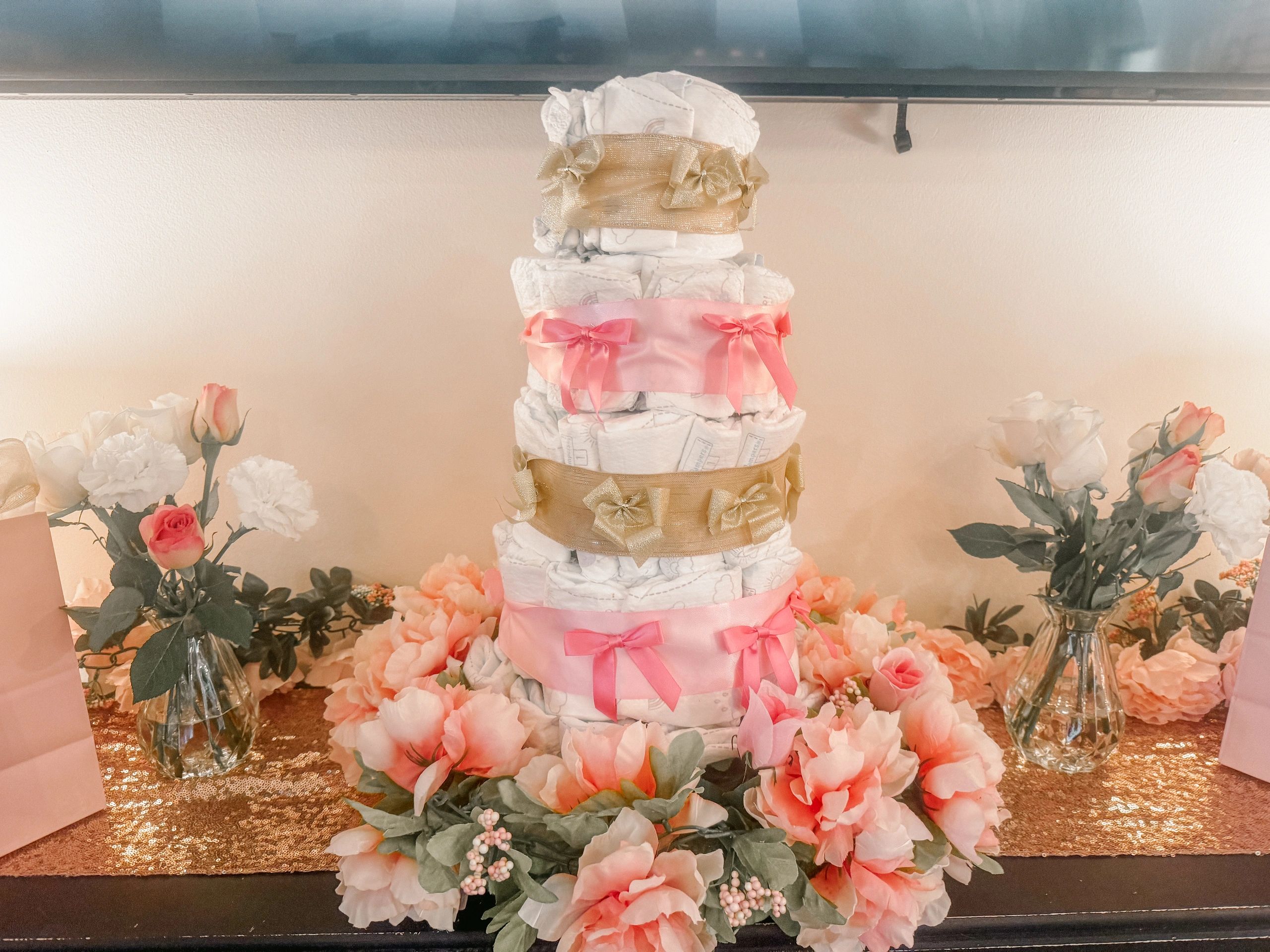 Decorative diaper cake surrounded by flowers.