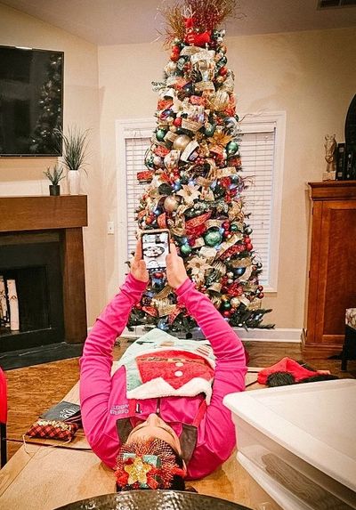 Person taking photo of decorated Christmas tree indoors.