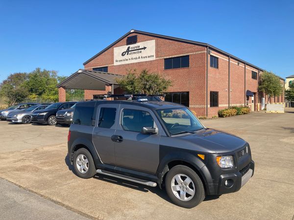 Gray SUV parked near a brick automotive building.