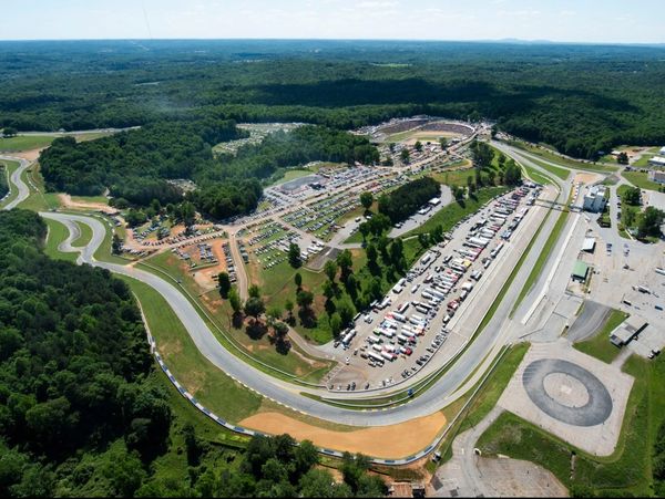 Aerial view of a race track surrounded by greenery and parking areas.