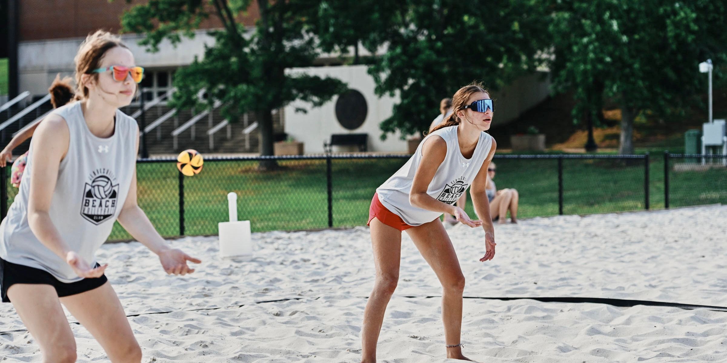 Two women playing beach volleyball on a sand court.