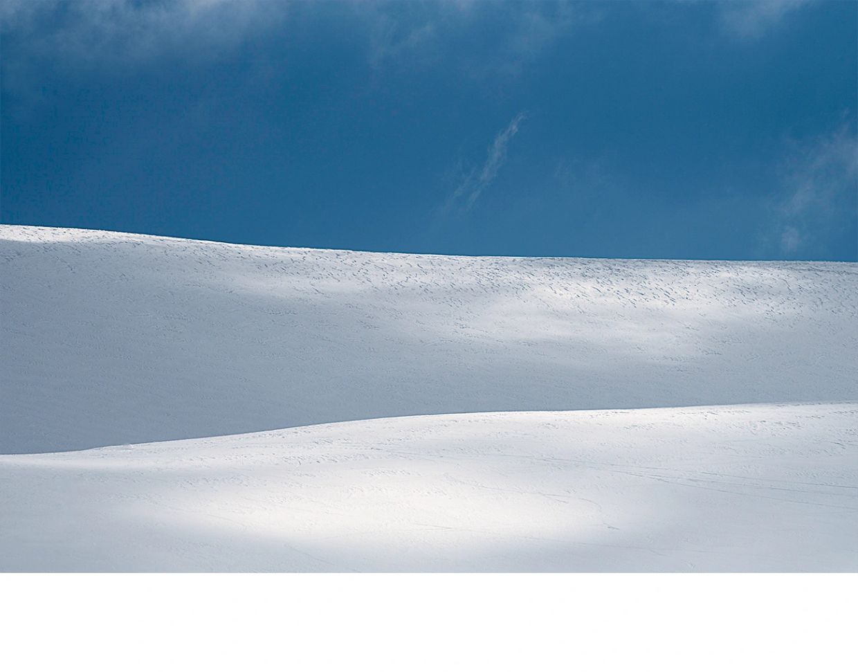 Snow-covered hills under a blue sky.
