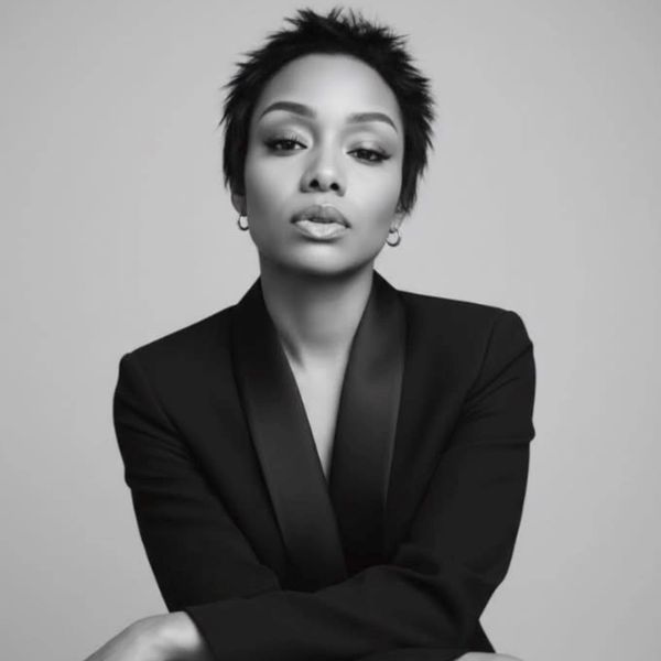 Confident woman in a black blazer posing for a monochrome portrait.