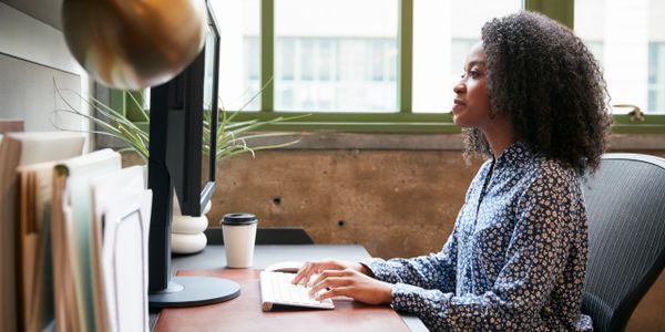 Woman focused on computer work in an office setting.