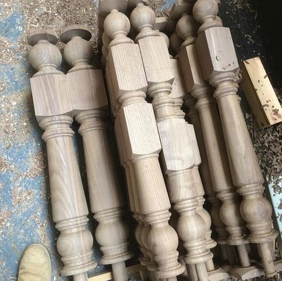 Several intricately carved wooden table legs laid out on a workshop floor.