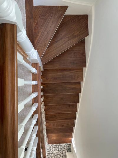 Top view of a wooden spiral staircase with white railings.