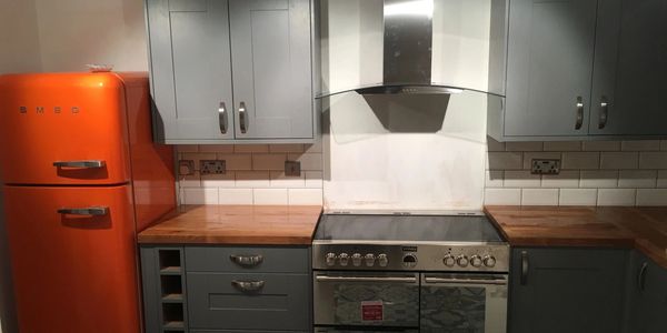 grey kitchen with orange fridge freezer and stainless steel large cooker