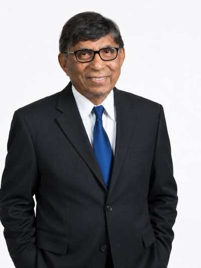 Smiling man in a black suit and blue tie.