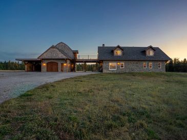 Spacious rustic stone house with garage at dusk.