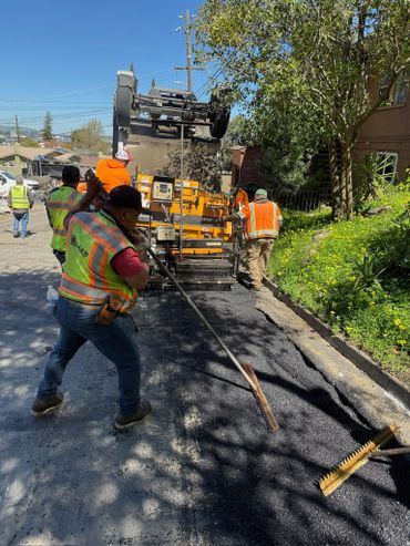 Workers paving a road with asphalt on a sunny day.