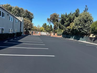 Empty parking lot beside a building on a clear sunny day.