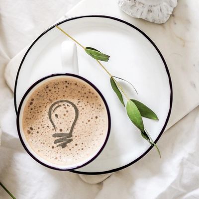 A cup of café latte with a frothy lightbulb 
