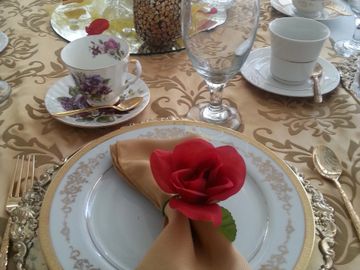 Fine dining setting with gold napkin and red rose and tea cups